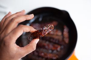 Vegan Tempeh bacon with frying pan in the back