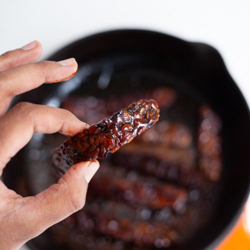 Vegan Tempeh bacon with frying pan in the back