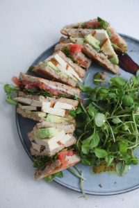 Vegan club sandwich on a plate with a small salad