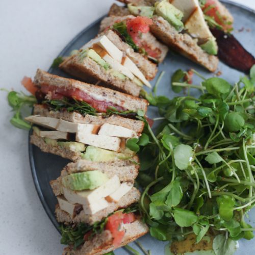 Vegan club sandwich on a plate with a small salad