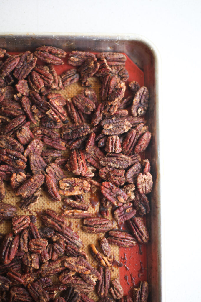 Roasted pecans on a baking sheet with a silicone liner