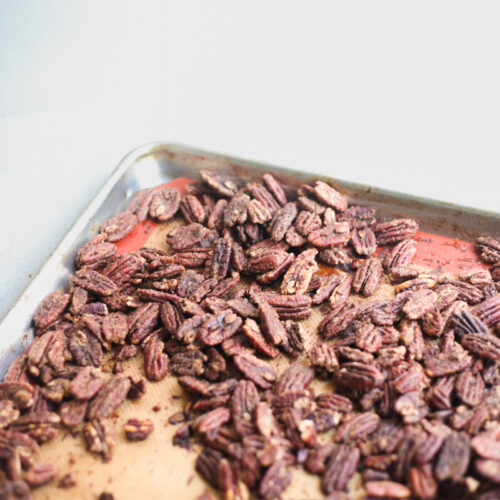 Baking tray covered with freshly roasted dark brown pecans